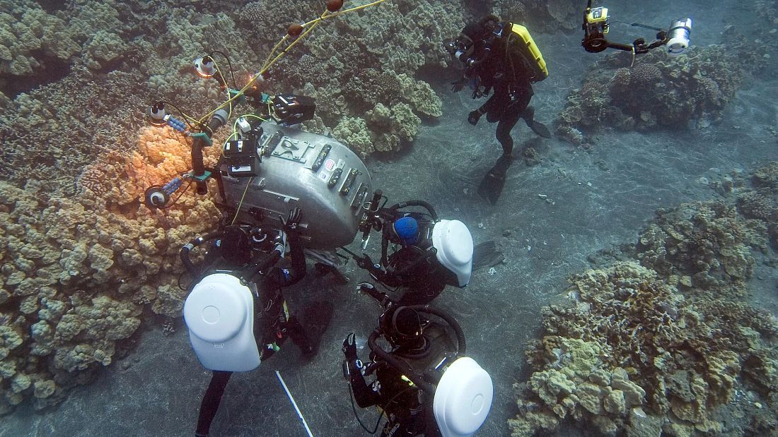 Divers inspecting large camera on ocean floor