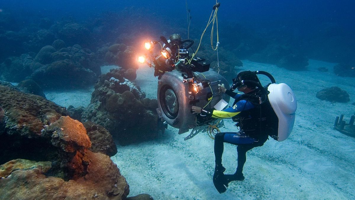 Scuba diver Howard Hall with large underwater camera on ocean floor
