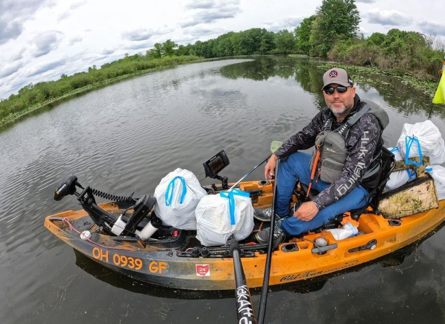 Angler on Old Town kayak with several full trash bags he collected on lake